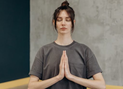 A woman meditating indoors with eyes closed, focusing on mindfulness and relaxation.